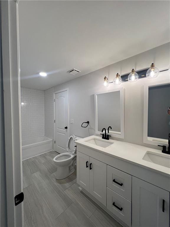 bathroom with dual vanity and toilet