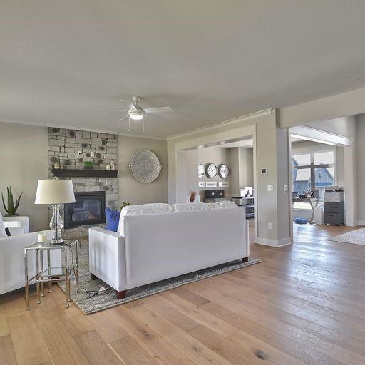 living room with hardwood / wood-style floors, ornamental molding, ceiling fan, and a fireplace