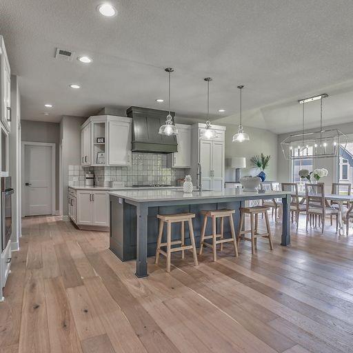 kitchen with custom exhaust hood, pendant lighting, a kitchen island, and light hardwood / wood-style flooring