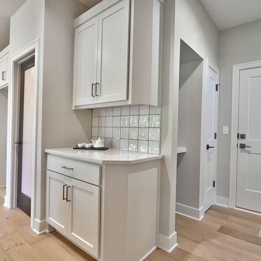 kitchen featuring white cabinetry, backsplash, and light wood-type flooring