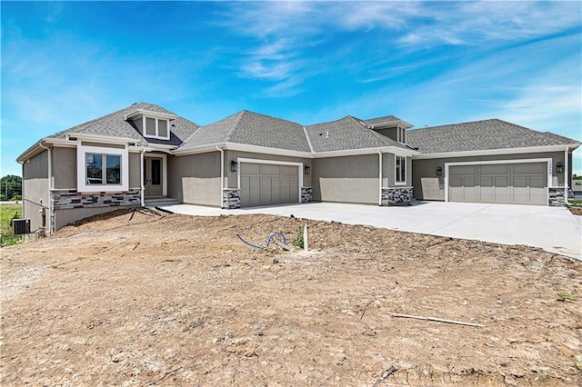 prairie-style home featuring an attached garage, stone siding, concrete driveway, and stucco siding