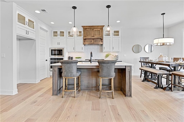 13028 S Constance St, Olathe, KS 66062 - kitchen with black microwave, oven, light wood-type flooring, tasteful backsplash, and light countertops