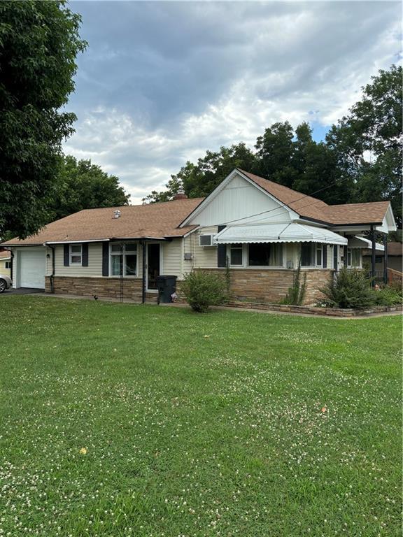 303 N Cayuga St, Frontenac, KS 66763 - ranch-style home with an attached garage, a front lawn, stone siding, and asphalt driveway