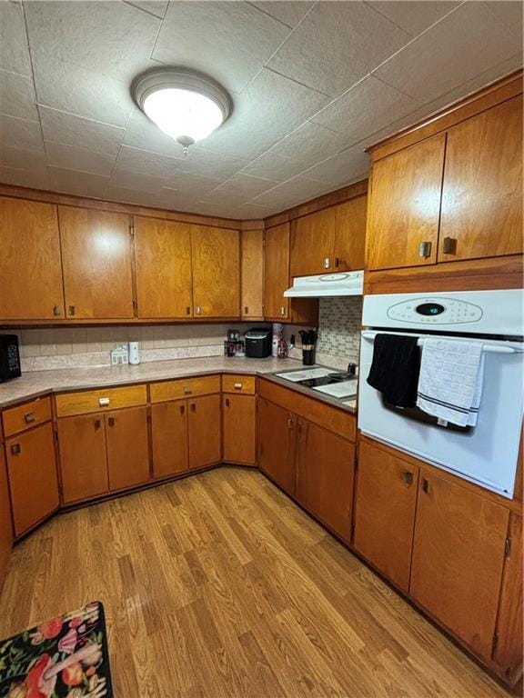 303 N Cayuga St, Frontenac, KS 66763 - kitchen featuring white appliances, under cabinet range hood, brown cabinetry, and light wood finished floors