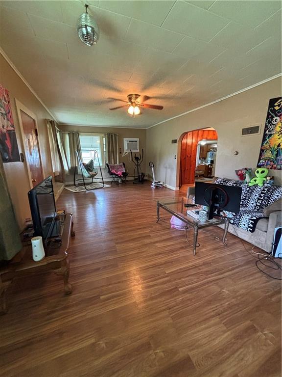 303 N Cayuga St, Frontenac, KS 66763 - living room with crown molding, wood finished floors, arched walkways, a wall mounted AC, and ceiling fan