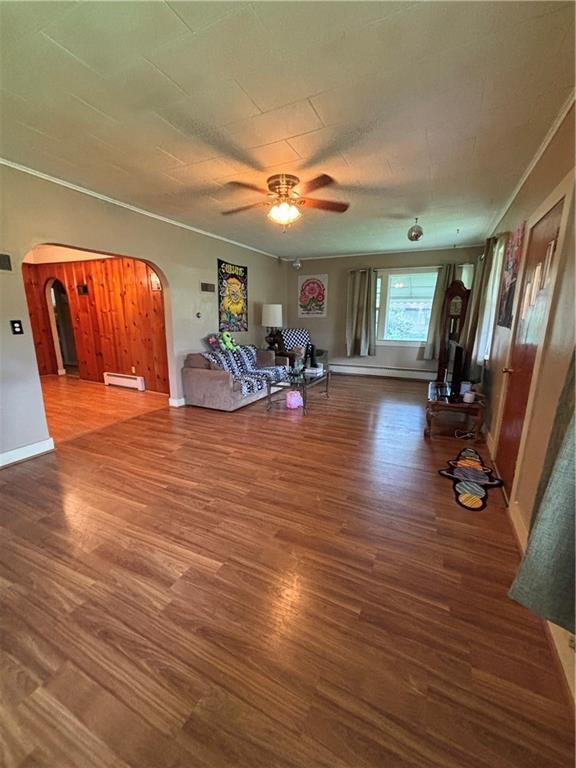 303 N Cayuga St, Frontenac, KS 66763 - living room with arched walkways, wood finished floors, a ceiling fan, and a baseboard heating unit
