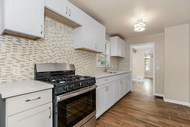 kitchen featuring dark hardwood / wood-style floors, sink, white cabinetry, stainless steel range with gas stovetop, and decorative backsplash