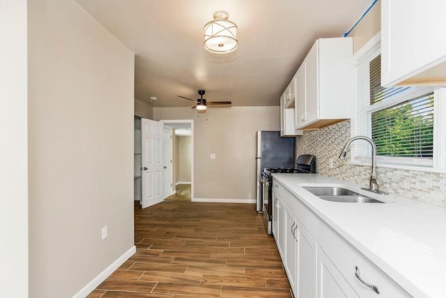 kitchen with wood-type flooring, white cabinets, stainless steel gas stove, and sink