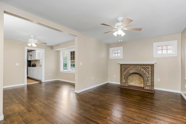 unfurnished living room featuring dark hardwood / wood-style flooring, ceiling fan, and a brick fireplace