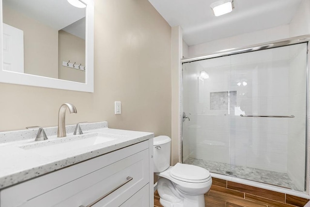 bathroom featuring wood-type flooring, an enclosed shower, vanity, and toilet