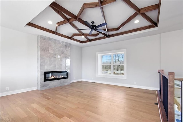 unfurnished living room with light wood-type flooring, a fireplace, coffered ceiling, and baseboards