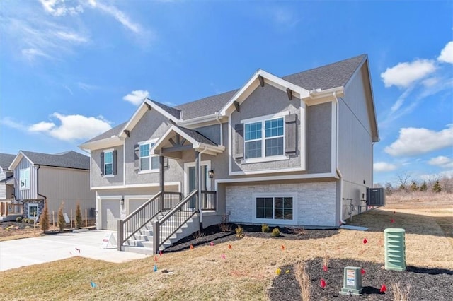 bi-level home with stucco siding, concrete driveway, an attached garage, cooling unit, and stone siding