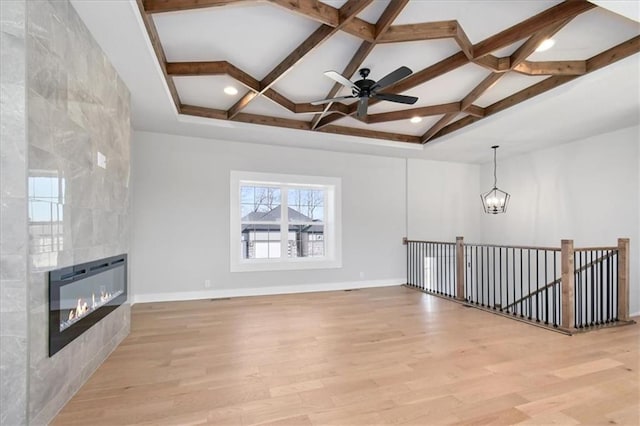 unfurnished living room with a fireplace, light wood-style floors, coffered ceiling, beamed ceiling, and baseboards