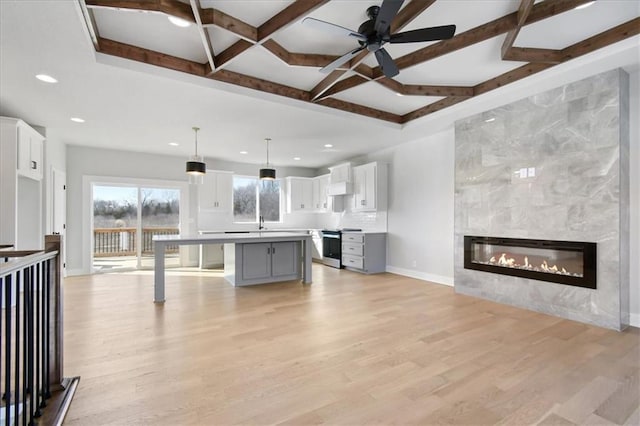 kitchen with stainless steel range with electric stovetop, light wood finished floors, and beamed ceiling