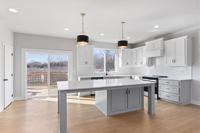 kitchen with light countertops, appliances with stainless steel finishes, a sink, and light wood-style floors