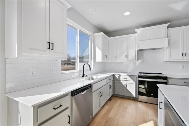 kitchen featuring a sink, light countertops, appliances with stainless steel finishes, light wood-type flooring, and backsplash