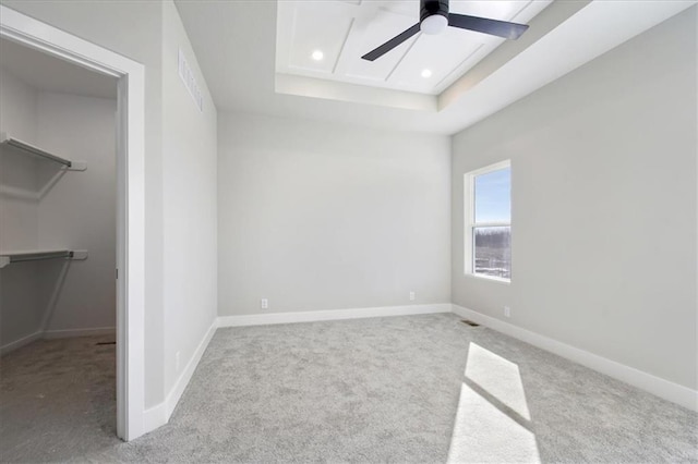 unfurnished bedroom featuring carpet floors, a tray ceiling, and baseboards