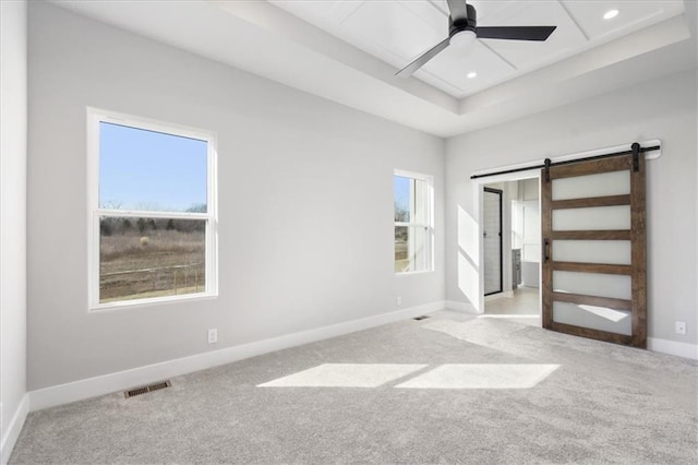 unfurnished bedroom featuring carpet floors, a barn door, visible vents, and baseboards