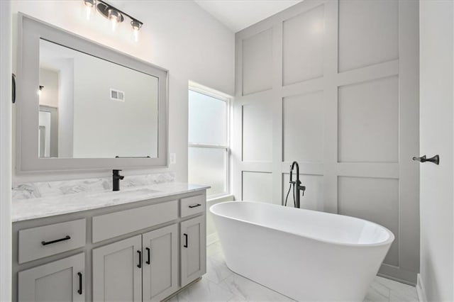 full bathroom featuring marble finish floor, visible vents, a freestanding bath, and vanity