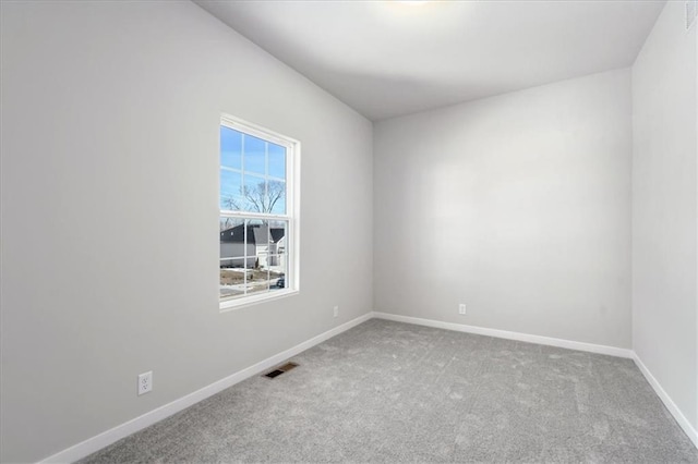 spare room featuring carpet, visible vents, and baseboards