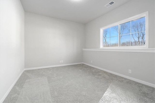 spare room with carpet, visible vents, and baseboards