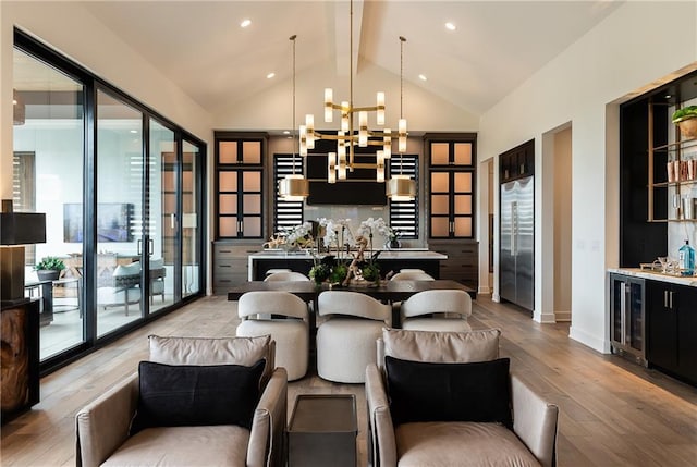 dining room with indoor bar, a healthy amount of sunlight, a notable chandelier, and light hardwood / wood-style floors