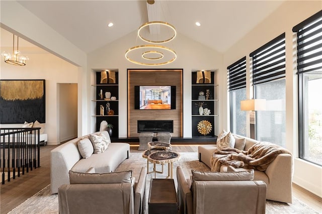 living room featuring an inviting chandelier, built in features, and light hardwood / wood-style flooring