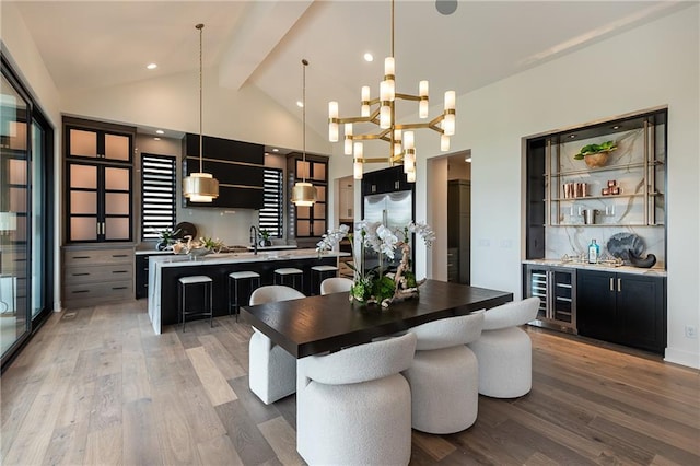 dining space featuring wine cooler, beamed ceiling, indoor wet bar, a notable chandelier, and hardwood / wood-style flooring