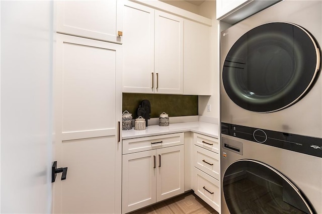 laundry area featuring cabinets and stacked washer and clothes dryer