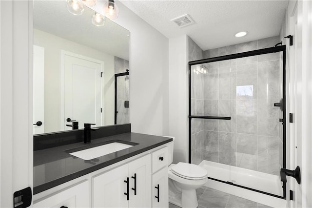 bathroom with a textured ceiling, vanity, toilet, and an enclosed shower