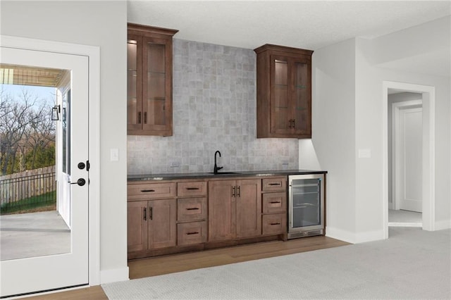 kitchen with light hardwood / wood-style floors, sink, beverage cooler, and tasteful backsplash