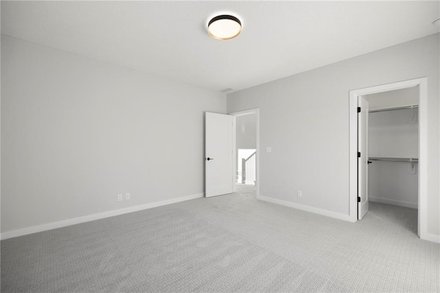 unfurnished bedroom with light colored carpet, a spacious closet, and a closet