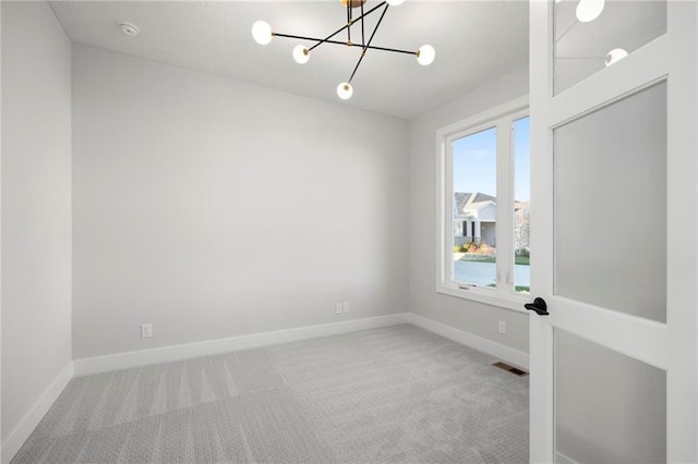 spare room with carpet and a notable chandelier