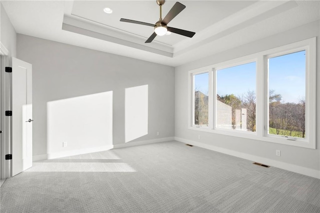 carpeted empty room with a tray ceiling and ceiling fan