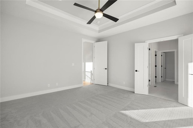 unfurnished bedroom with a raised ceiling, ceiling fan, and light colored carpet