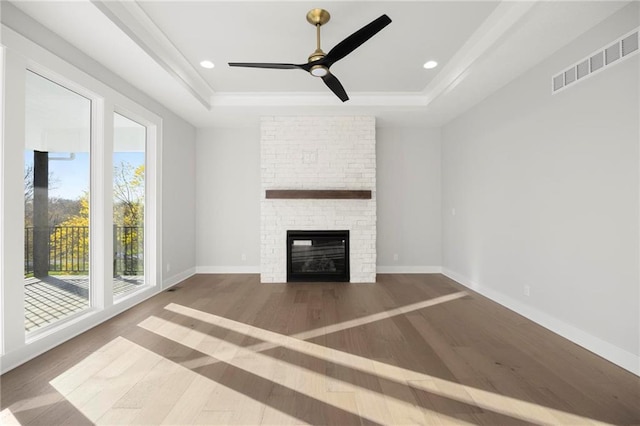 unfurnished living room featuring a fireplace, hardwood / wood-style flooring, a raised ceiling, and ceiling fan