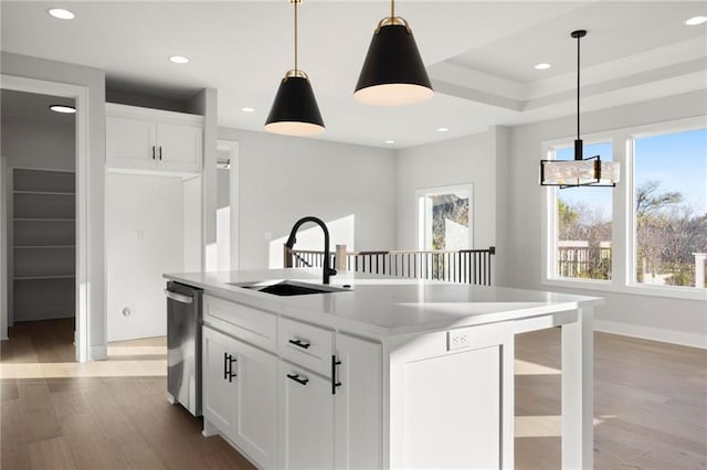 kitchen with white cabinets, decorative light fixtures, a center island with sink, and sink