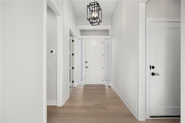 hallway with a chandelier and light hardwood / wood-style floors