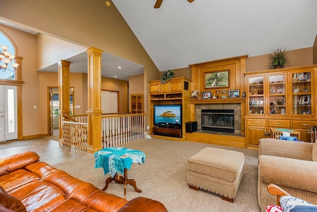 living room featuring a tiled fireplace, decorative columns, high vaulted ceiling, light tile patterned floors, and ceiling fan