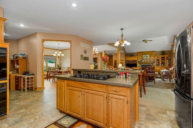 kitchen with ceiling fan with notable chandelier, black gas cooktop, decorative light fixtures, and stainless steel refrigerator