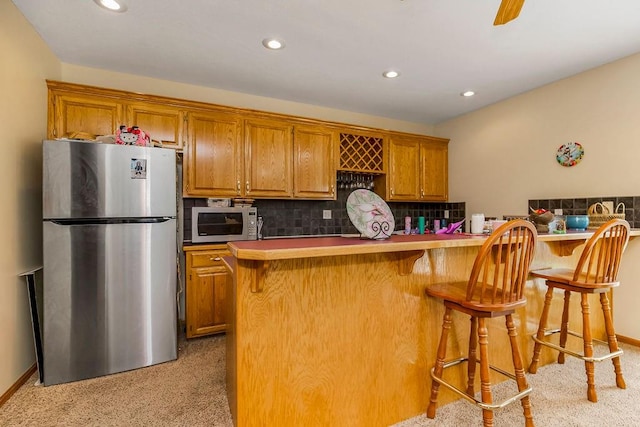 kitchen featuring a kitchen breakfast bar, stainless steel appliances, kitchen peninsula, and tasteful backsplash