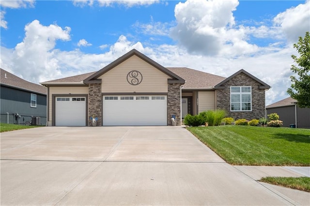 view of front of property featuring a garage, cooling unit, and a front lawn