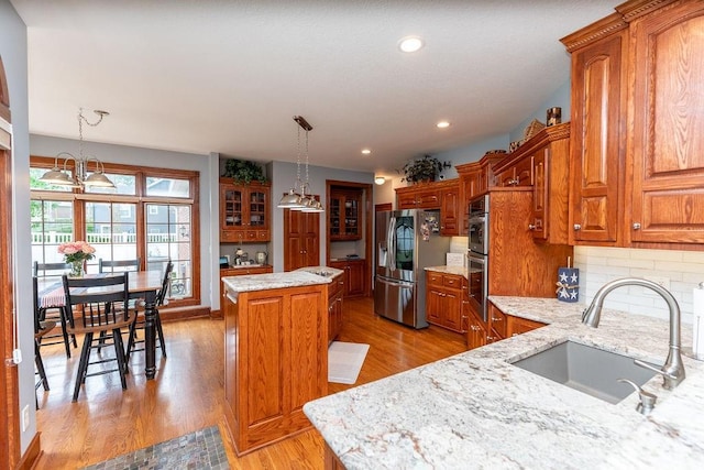 kitchen featuring sink, tasteful backsplash, decorative light fixtures, a center island, and stainless steel fridge