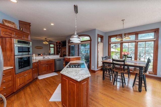 kitchen with appliances with stainless steel finishes, a kitchen island, decorative light fixtures, sink, and kitchen peninsula