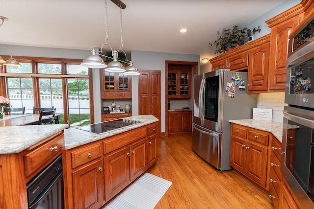 kitchen featuring pendant lighting, light hardwood / wood-style flooring, stainless steel appliances, tasteful backsplash, and light stone countertops