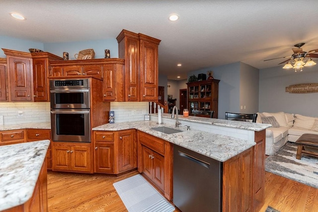 kitchen featuring appliances with stainless steel finishes, sink, light hardwood / wood-style floors, and kitchen peninsula