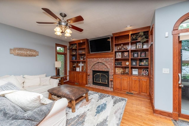 living room with ceiling fan, a healthy amount of sunlight, a fireplace, and light hardwood / wood-style floors