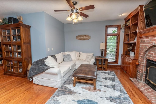 living room with ceiling fan, a fireplace, and hardwood / wood-style floors