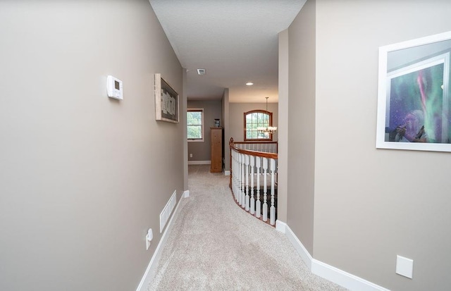 hallway featuring a chandelier and light carpet