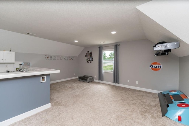 additional living space featuring lofted ceiling, light carpet, and a textured ceiling